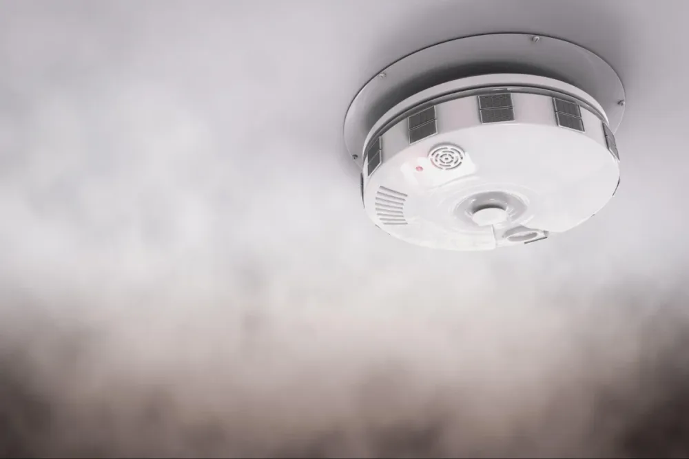 Ceiling smoke detector surrounded by smoke