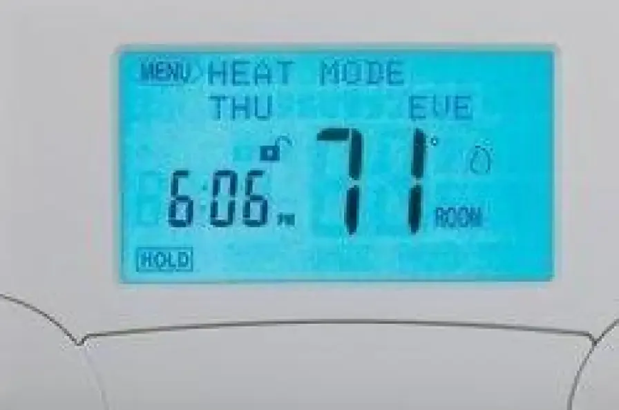 Digital thermostat displaying heat mode and room temperature
