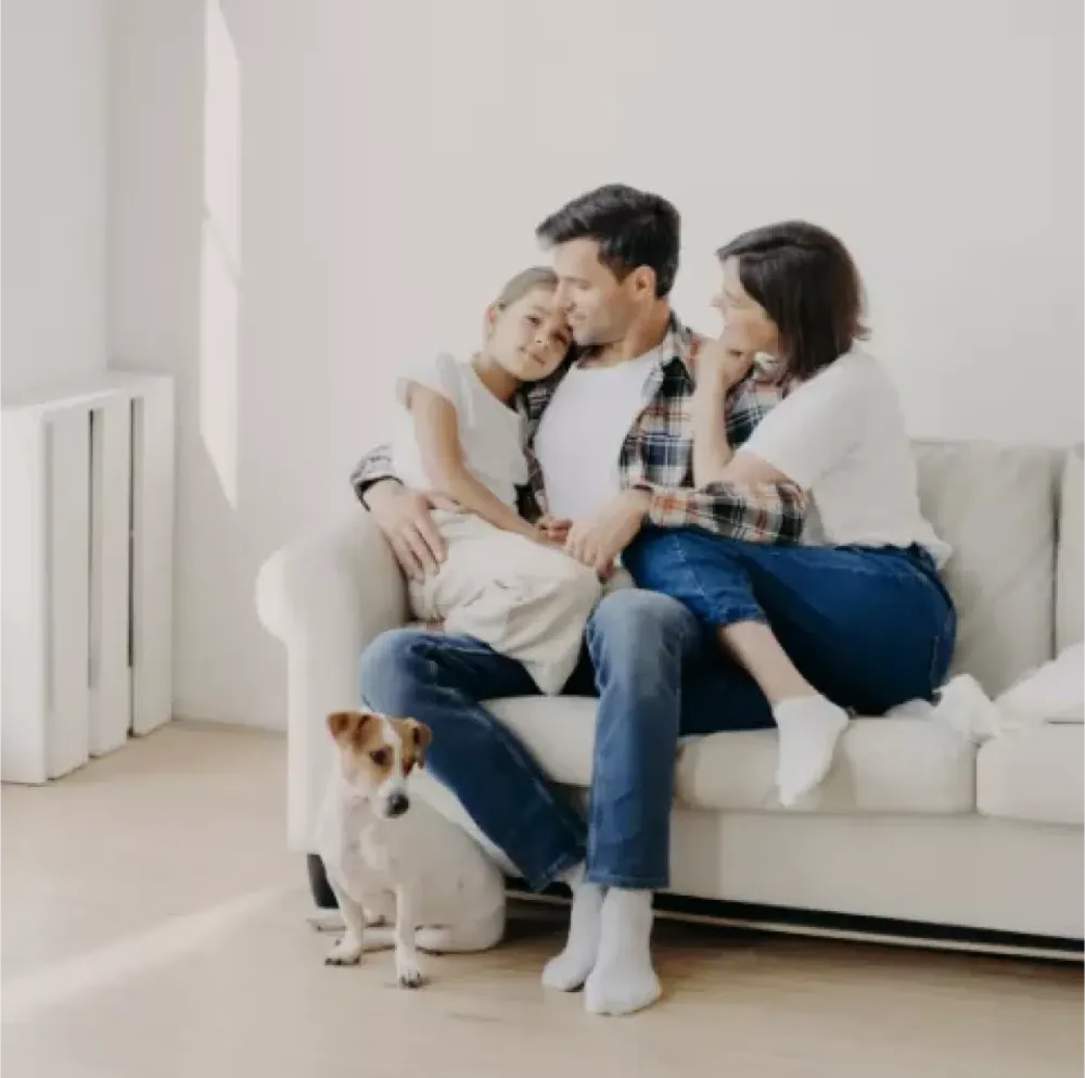 Family sitting together on a sofa with a dog