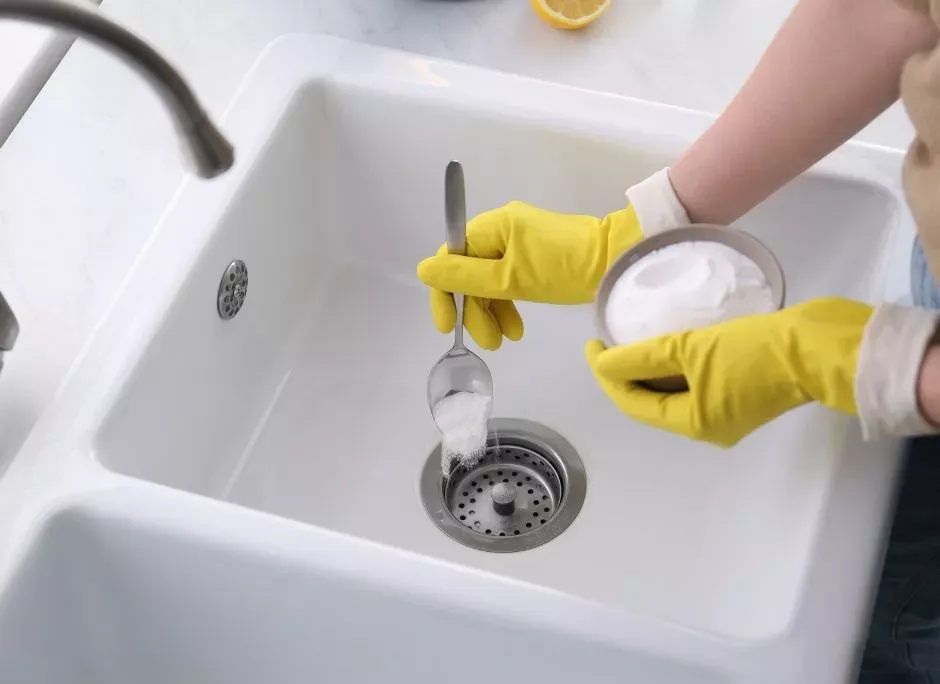 Gloved hands cleaning a sink drain
