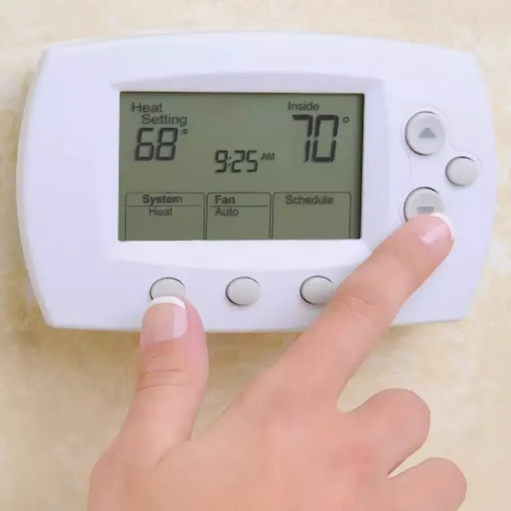 Hand adjusting a digital thermostat