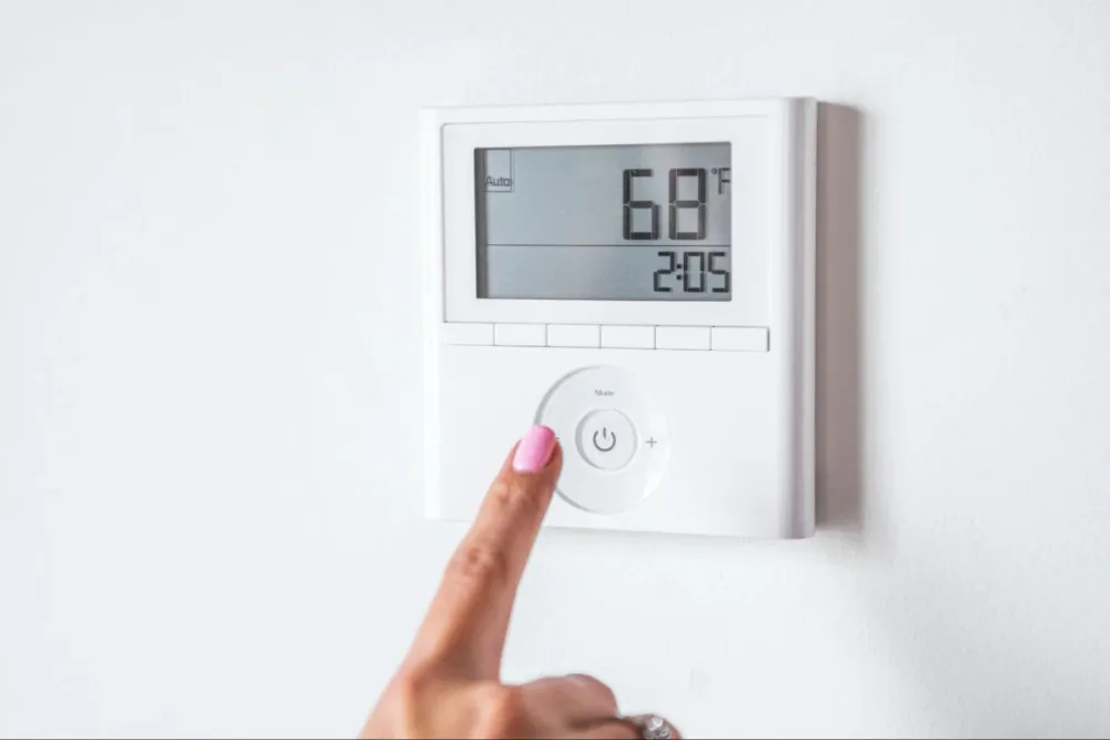 Hand adjusting a wall thermostat