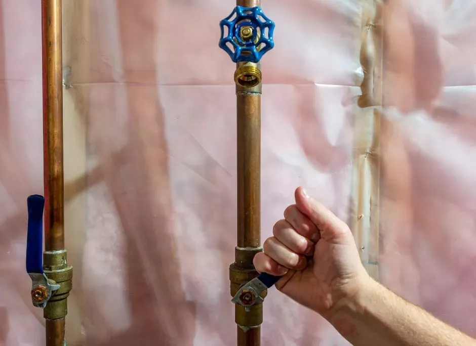Hand reaching for a water shutoff valve