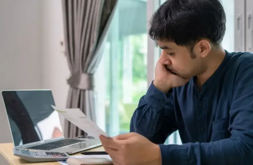 Homeowner reviewing bills beside a laptop