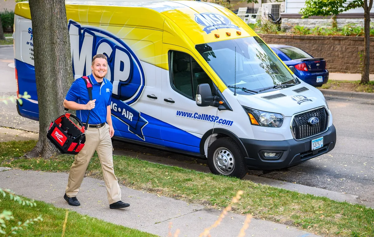 MSP technician carrying tools beside a service van