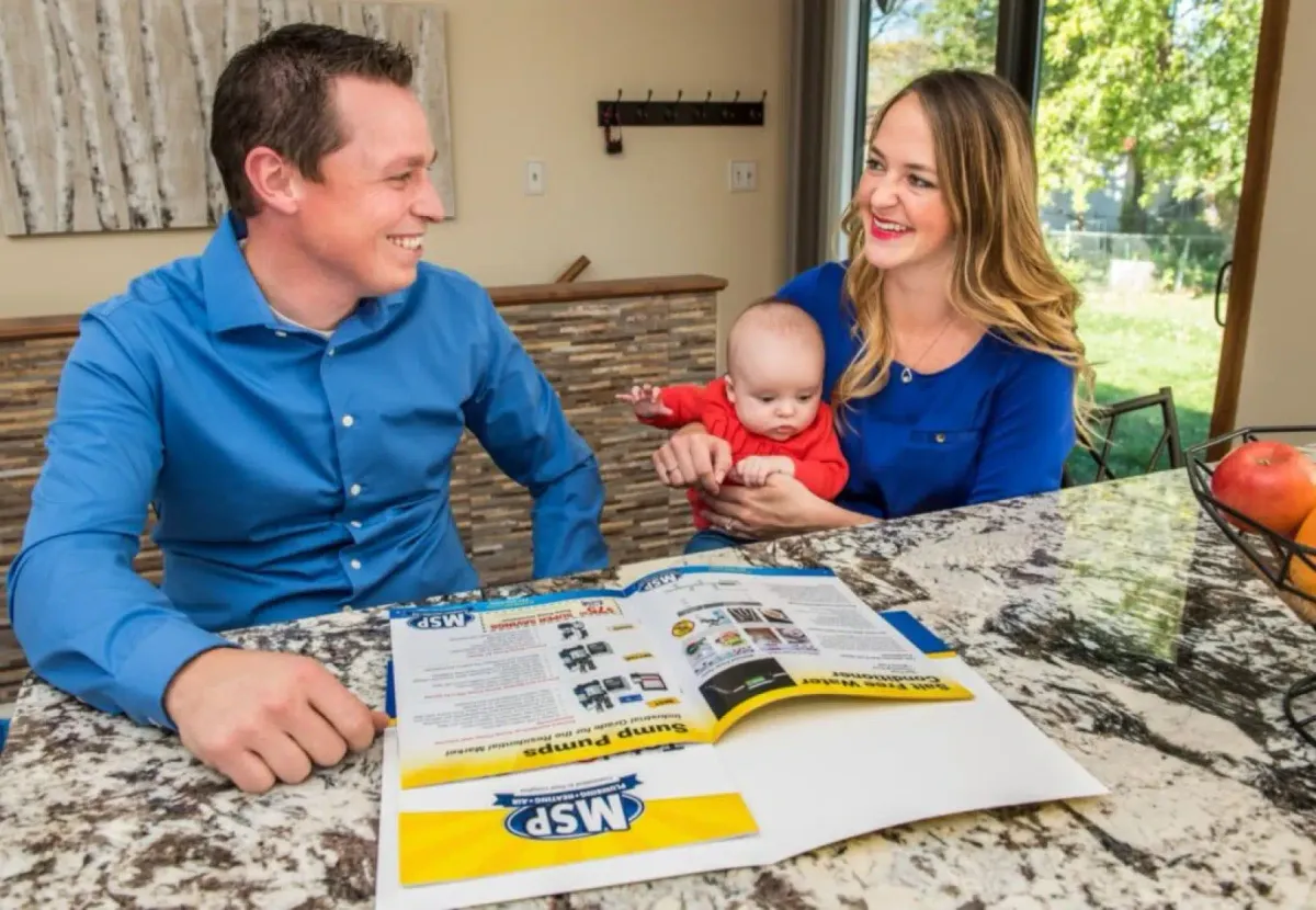 MSP technician reviewing a service brochure with a homeowner and baby