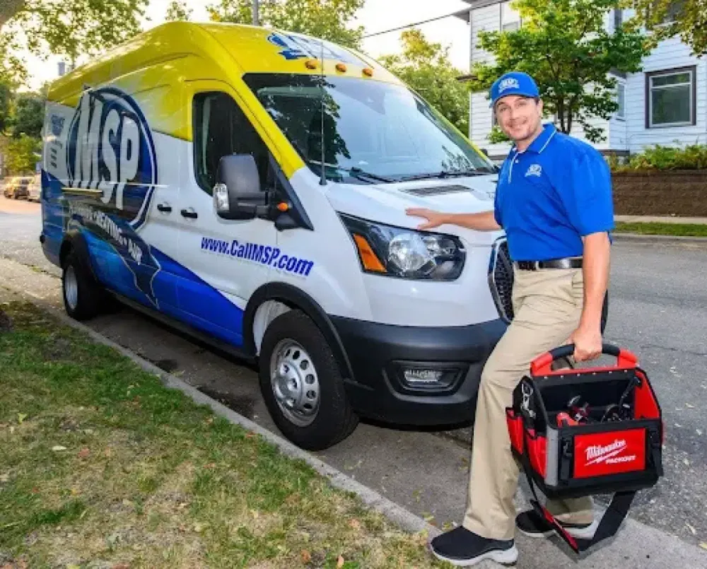 MSP technician with a tool bag beside a service van