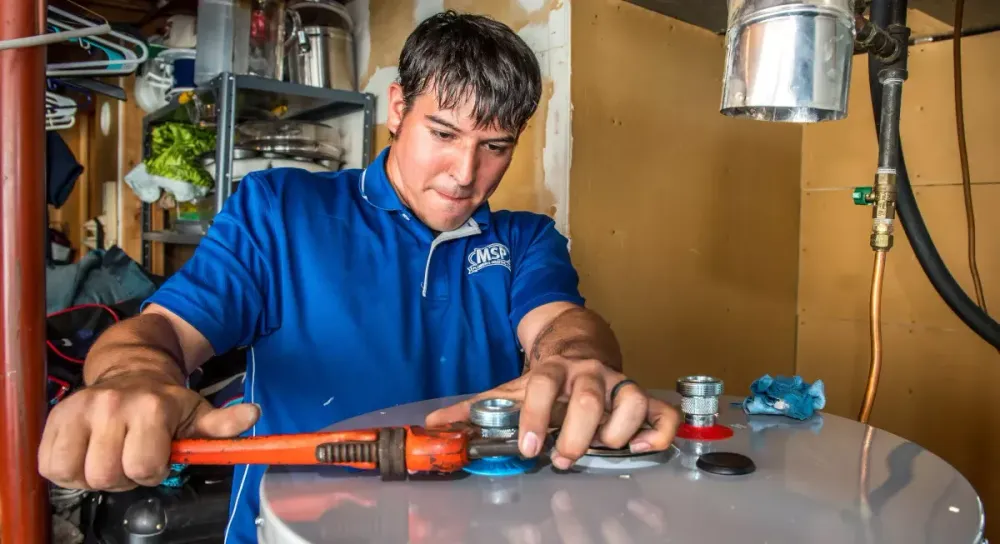 MSP technician using a wrench on a water heater