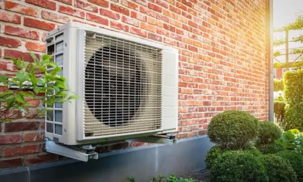 Outdoor ductless heat pump mounted beside a brick house