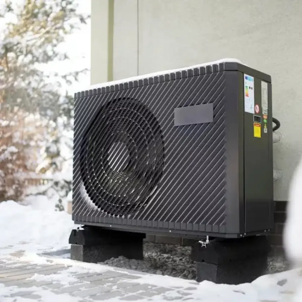 Outdoor heat pump beside a house in winter