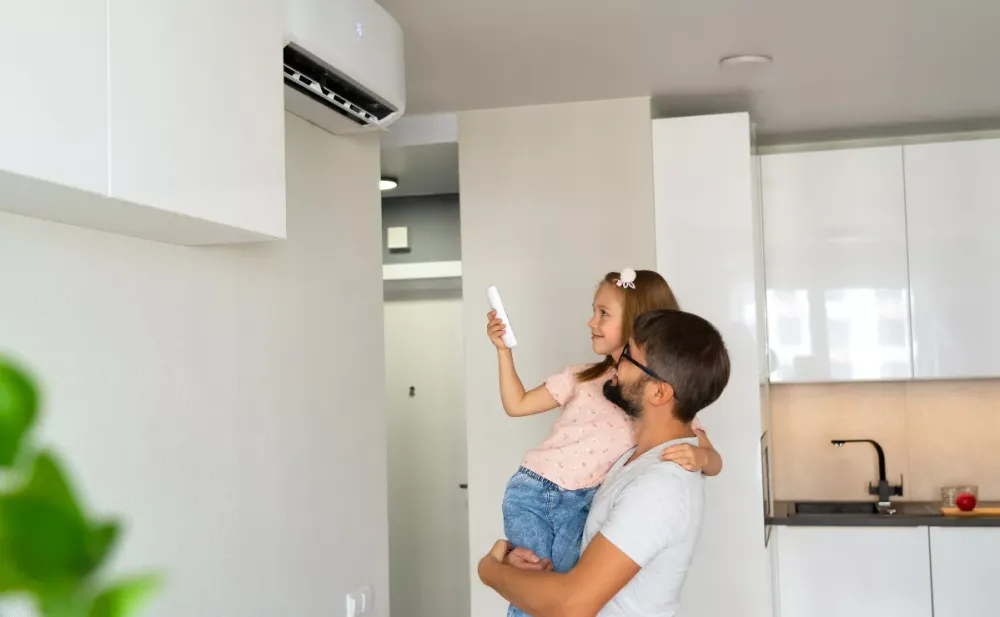 Parent holding a child beneath a ductless indoor unit