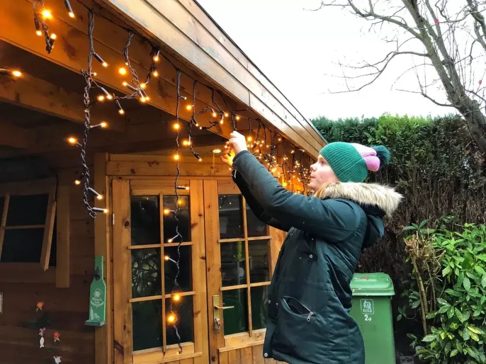 Person hanging exterior string lights
