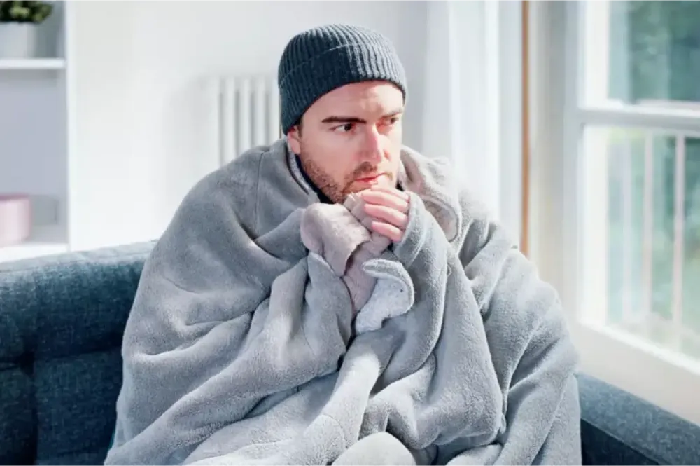 Person wrapped in a blanket in a cold room