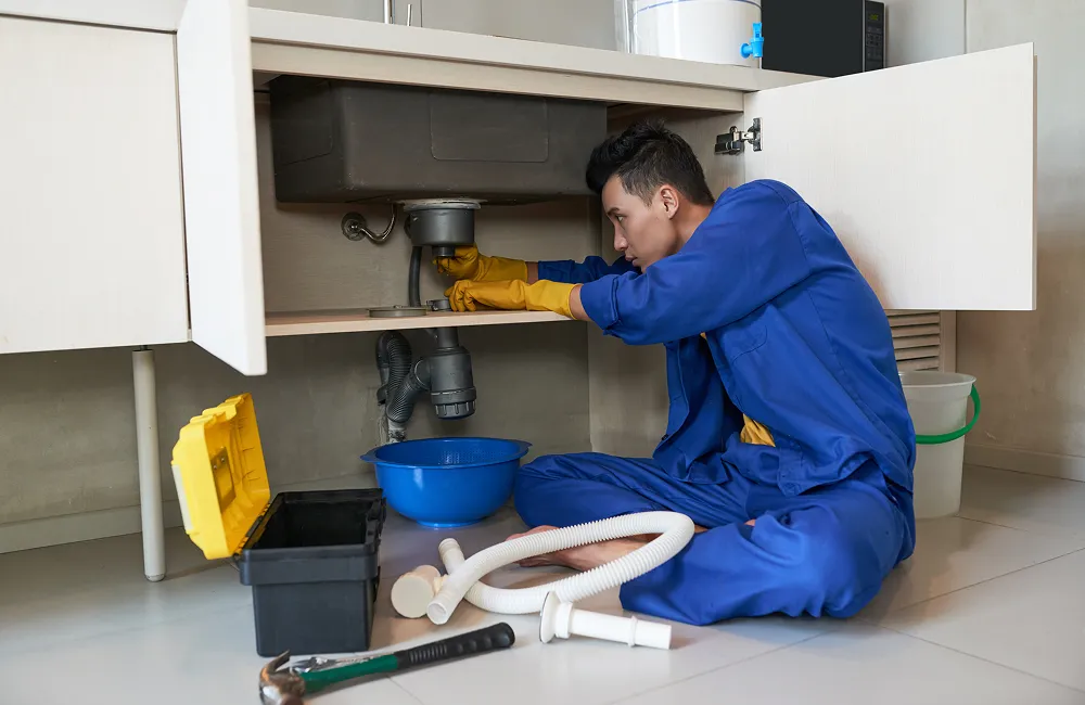 Plumber repairing the drain under a kitchen sink