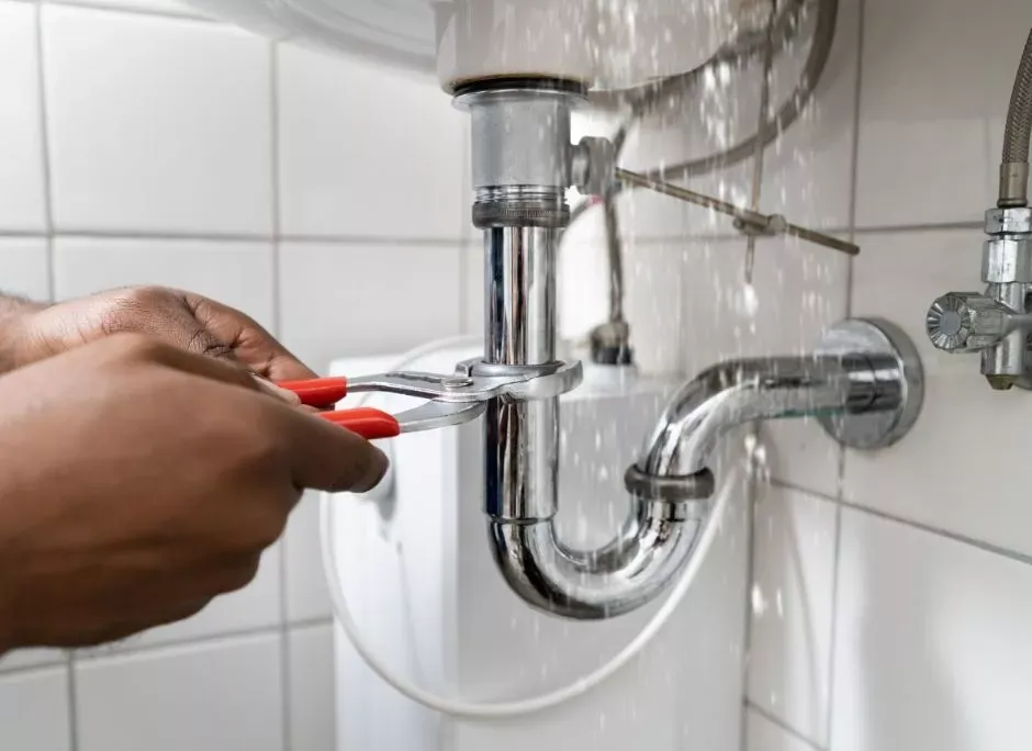 Plumber tightening the trap beneath a sink