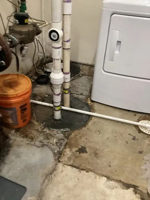 Sewer ejector pump basin and pipes in a utility room