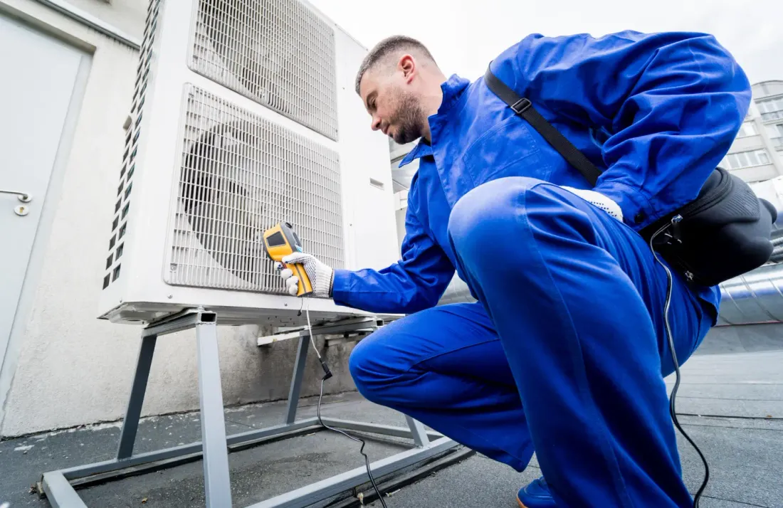 Technician checking an outdoor HVAC unit with a handheld instrument