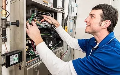 Technician checking wiring inside a furnace