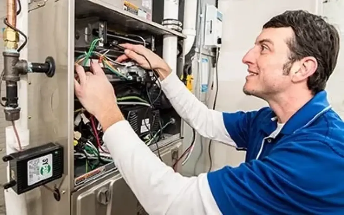 Technician checking wiring inside a furnace