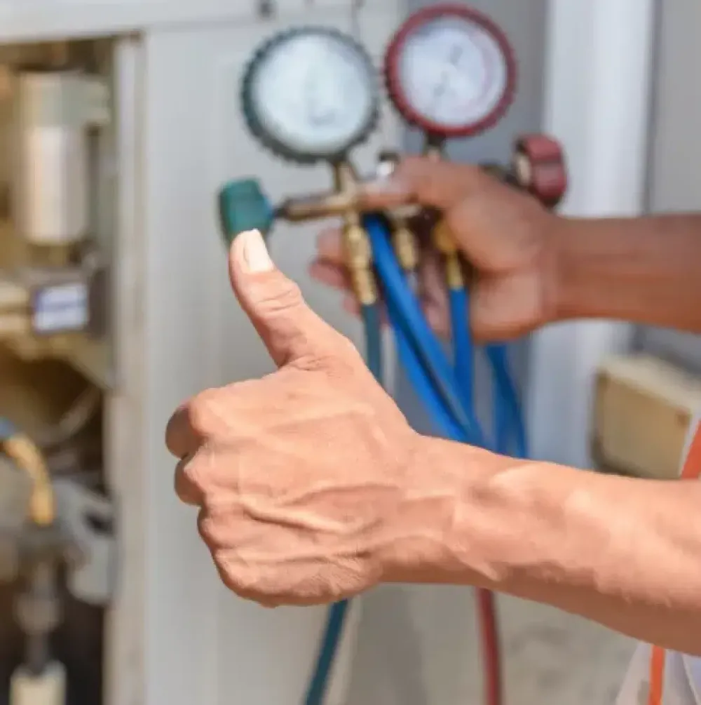 Technician holding refrigerant gauges and giving a thumbs-up