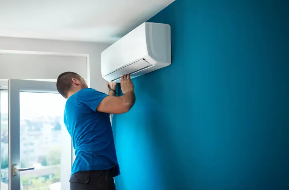 Technician servicing a wall-mounted ductless air conditioner