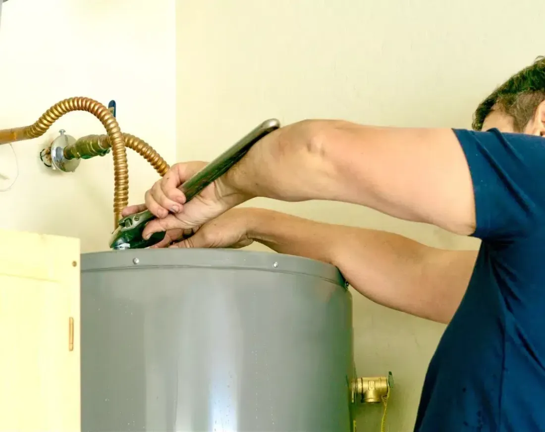 Technician working on connections at the top of a water heater