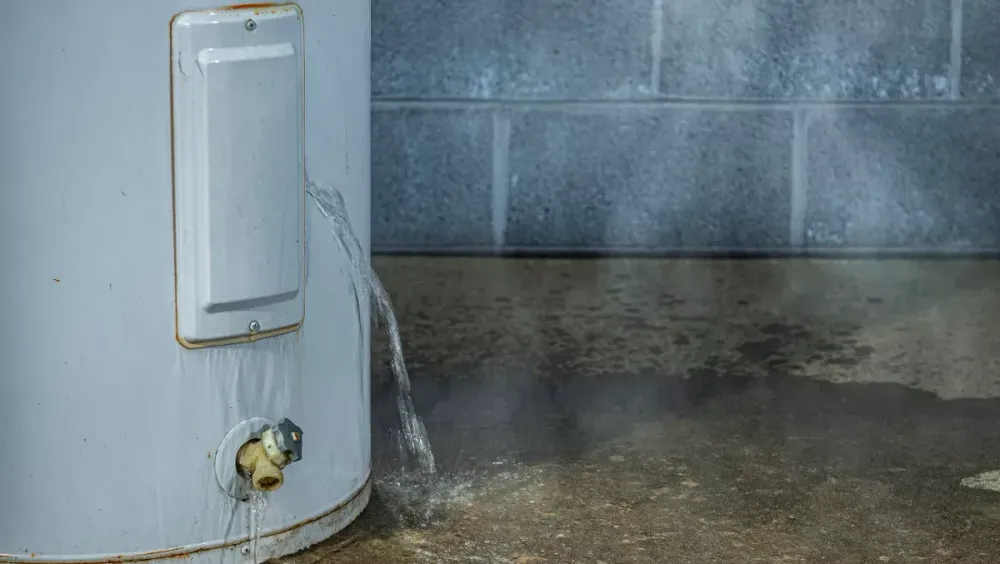 Water leaking onto the floor beside a tank water heater