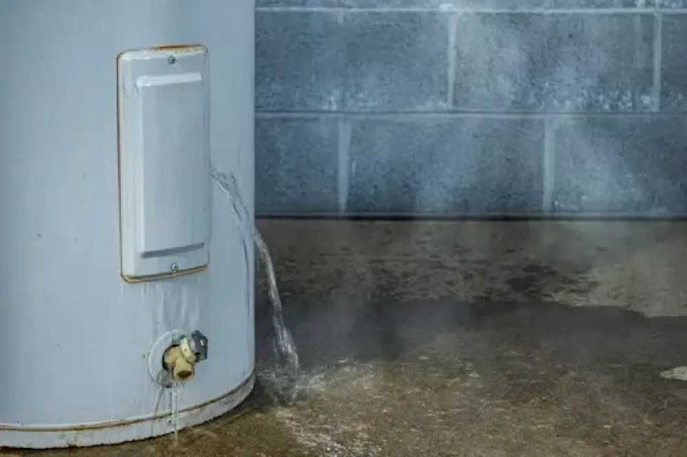 Water leaking onto the floor beside a tank water heater