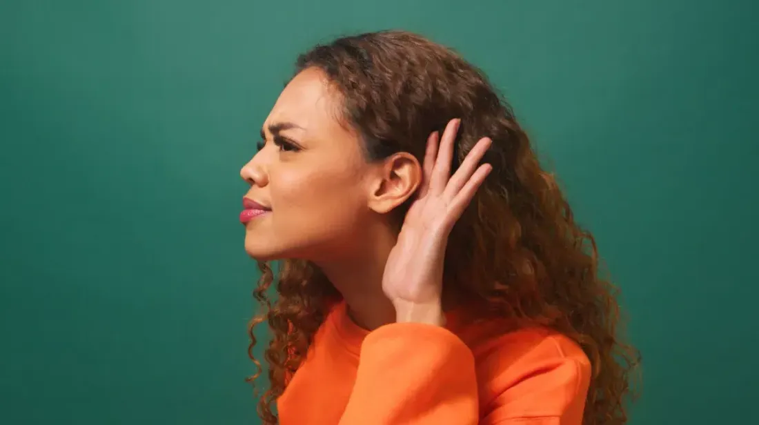 Woman cupping her hand behind her ear to listen