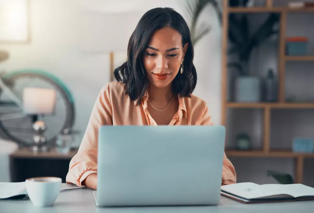 Woman researching on a laptop at a kitchen table