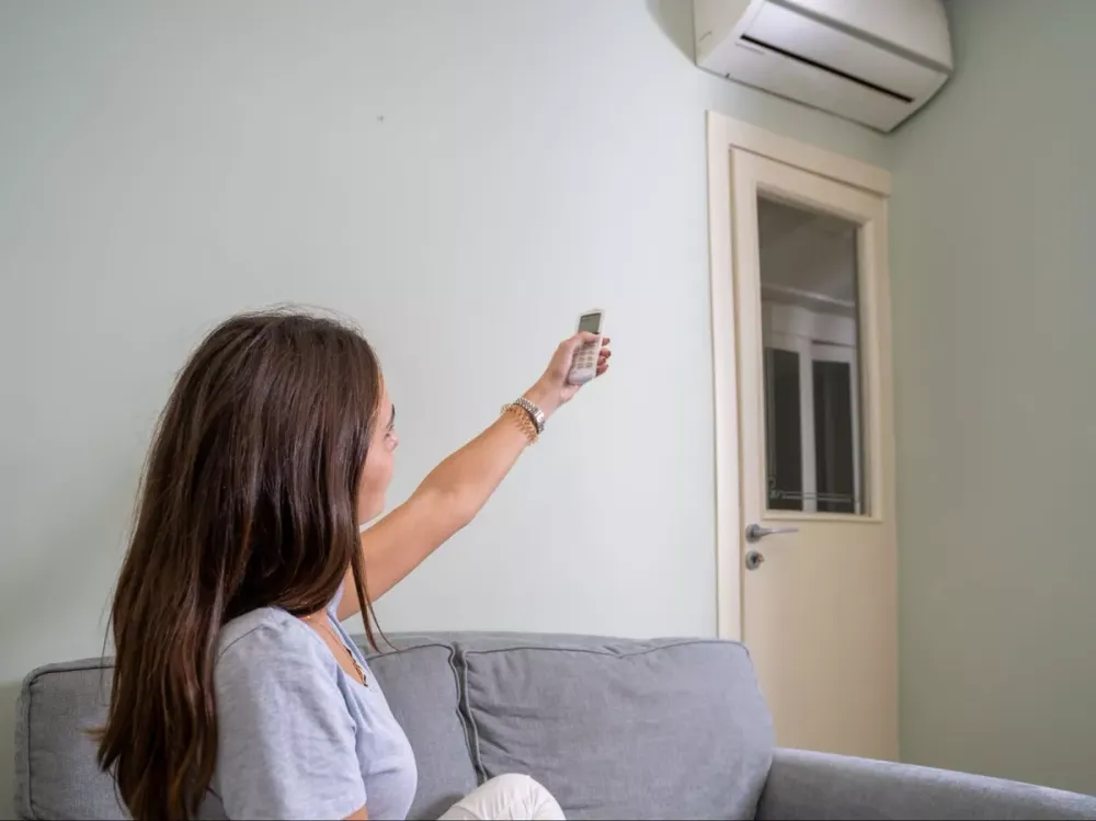Woman using a remote to control a wall-mounted ductless unit