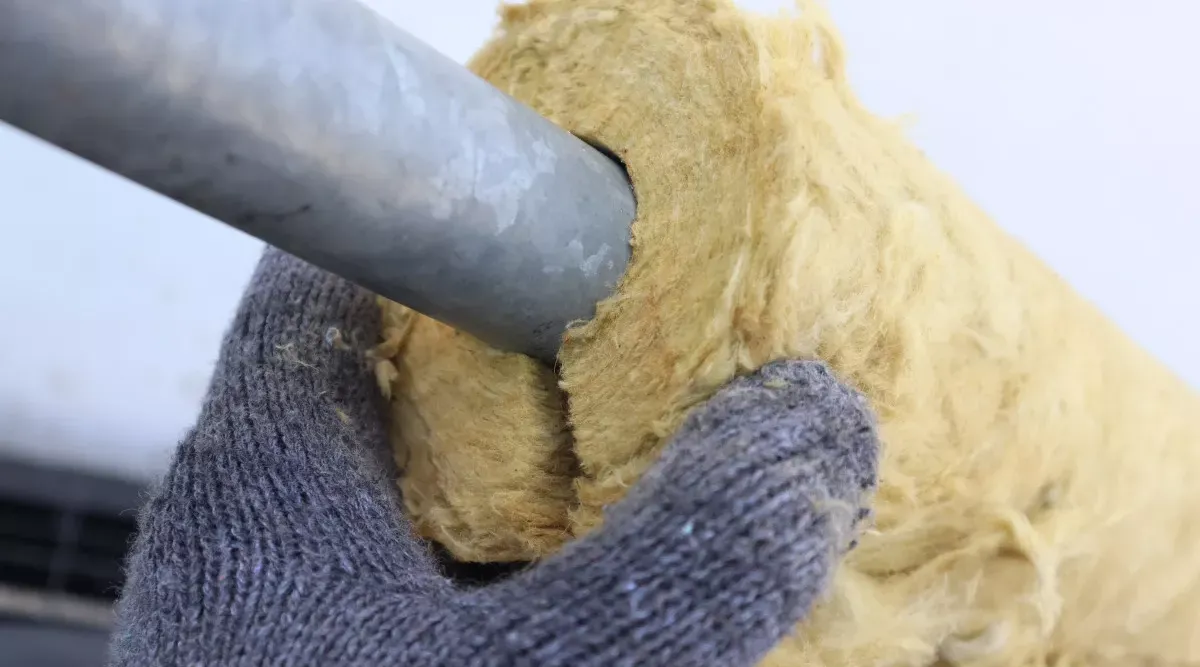 Worker putting insulation on a pipe