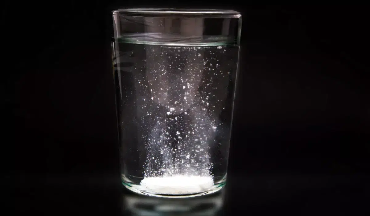 a glass of water with visible floating particles inside